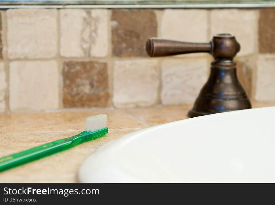 Tooth brush resting on edge of bathroom sink ready for use. Tooth brush resting on edge of bathroom sink ready for use