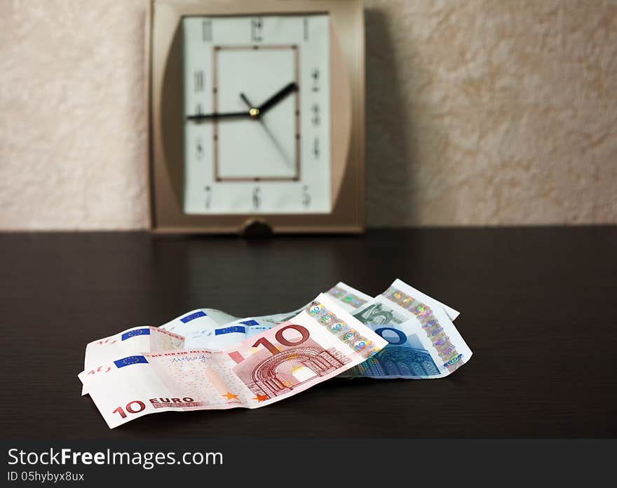 Money On The Table And Wall Clock From Behind