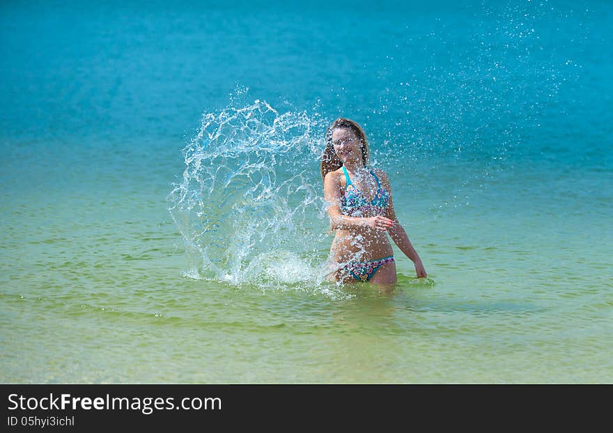 Young woman beating the water with his hands and makes a splash. Young woman beating the water with his hands and makes a splash