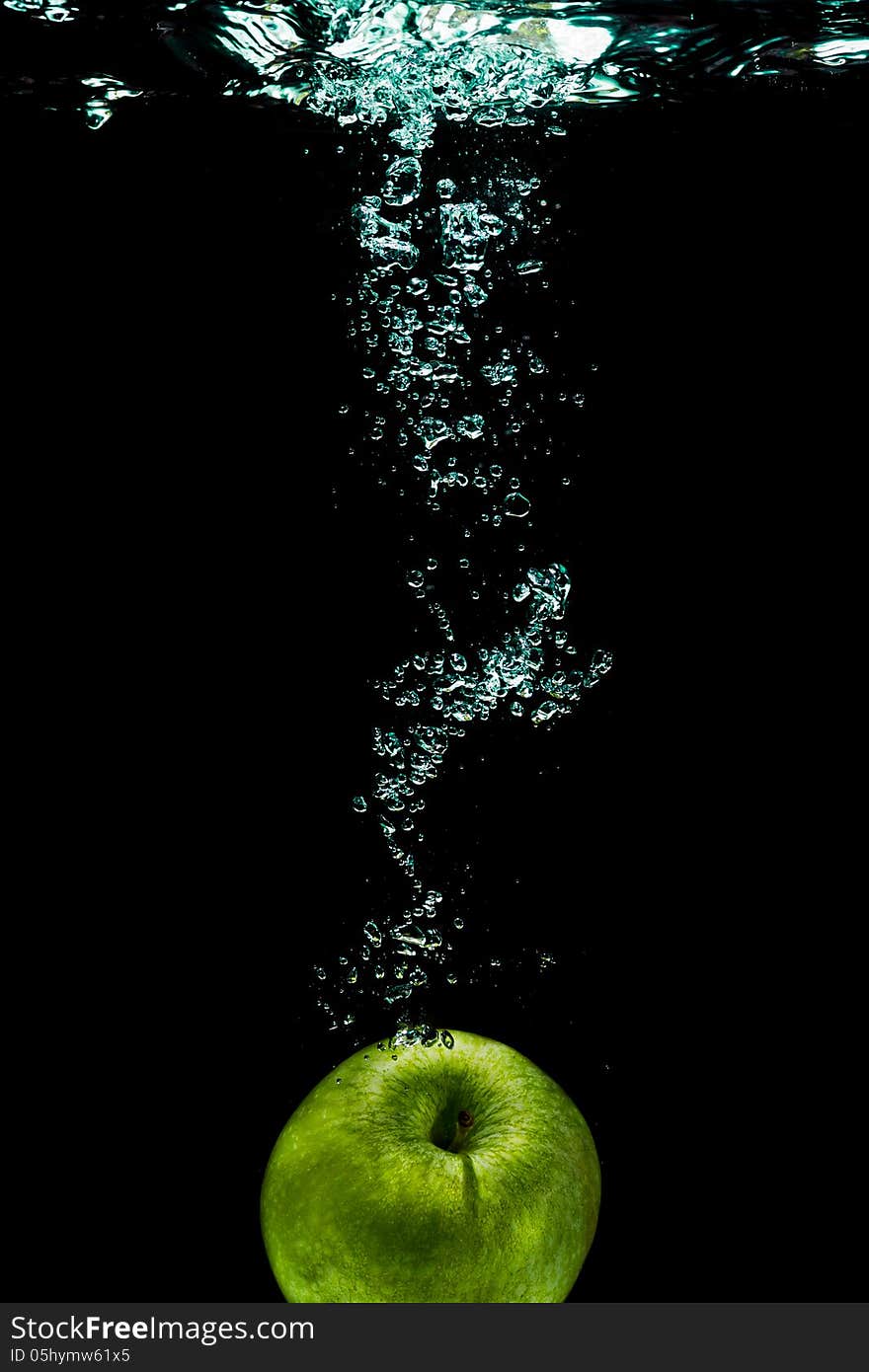 Green apple with splashing water on a black background. Green apple with splashing water on a black background