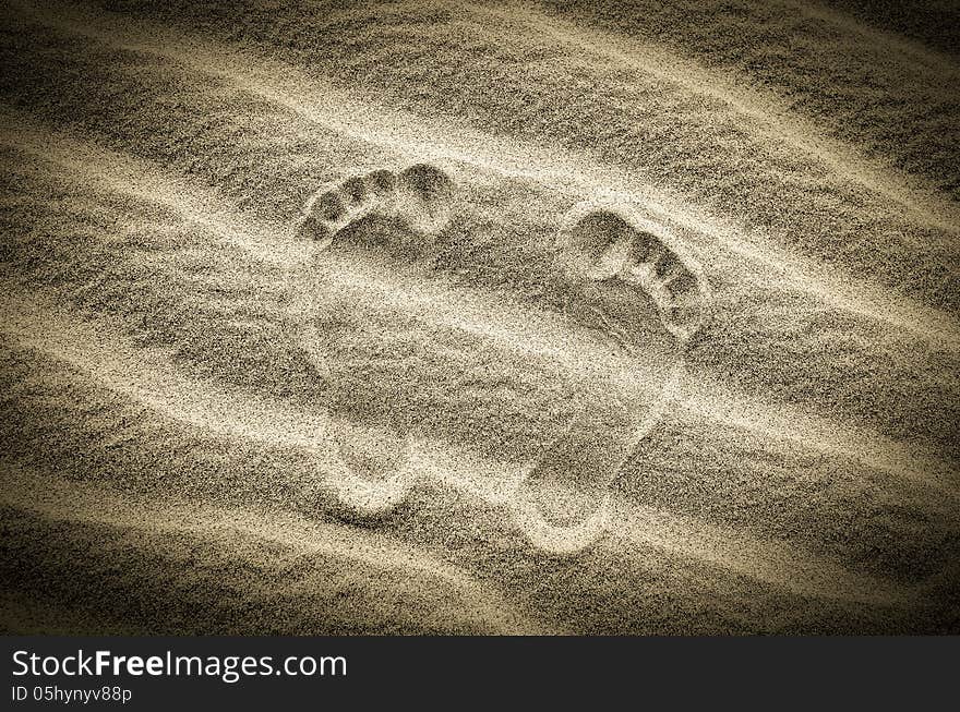 Two footprints in sand on the desert beach, vintage image