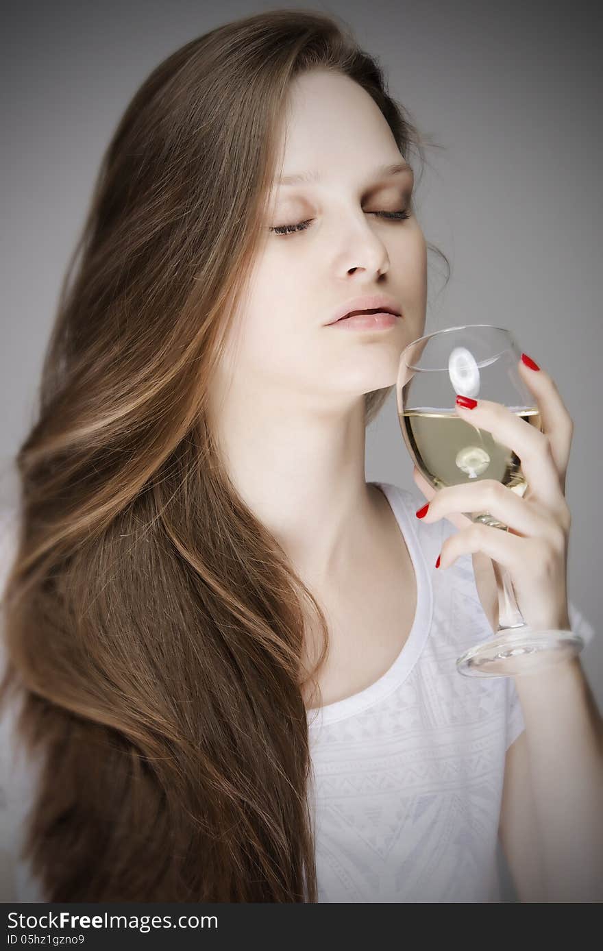 Beautiful dreamy woman smelling a glass of white wine