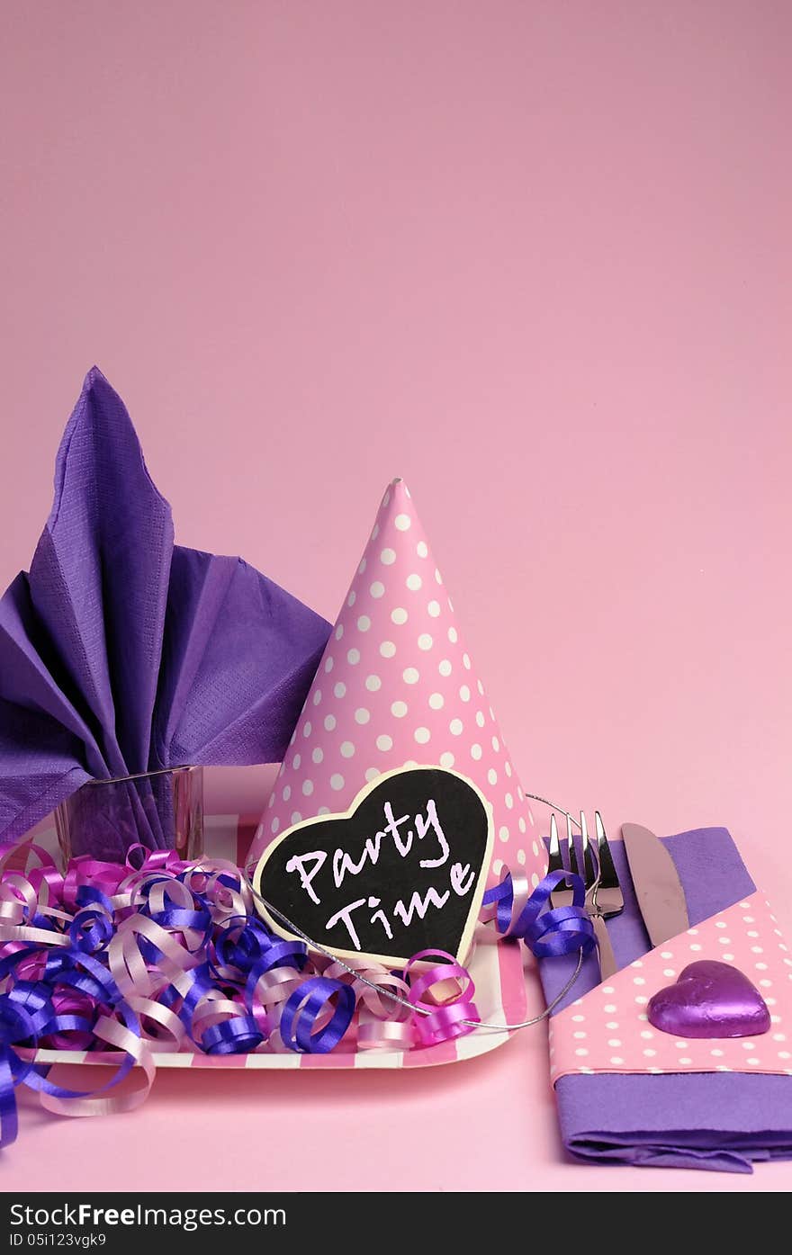 Pink and purple theme party table setting decorations, against a pale pink background. vertical with copy space for your text here. Pink and purple theme party table setting decorations, against a pale pink background. vertical with copy space for your text here.