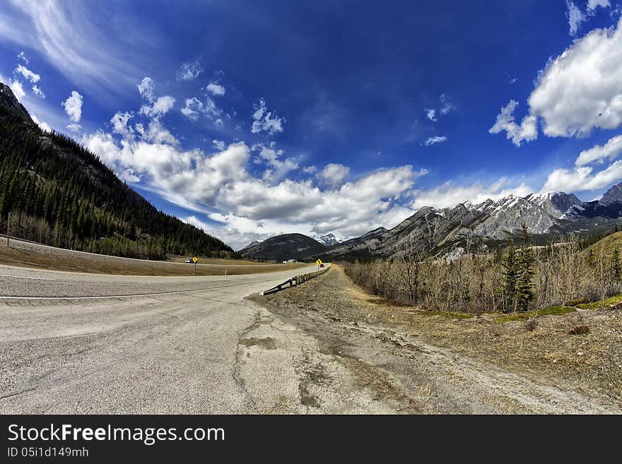 Road in the Canadian rocky mountains in Spring thru a fisheye lens. Road in the Canadian rocky mountains in Spring thru a fisheye lens