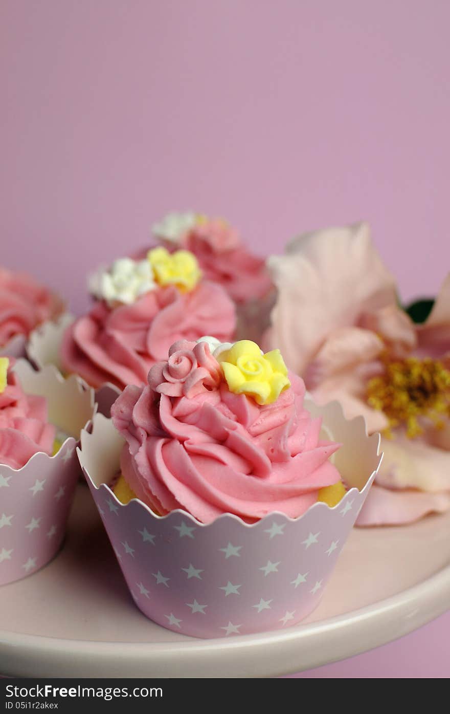 Beautiful pink decorated cupcakes on pink cake stand -  Vertical close up with bokeh.