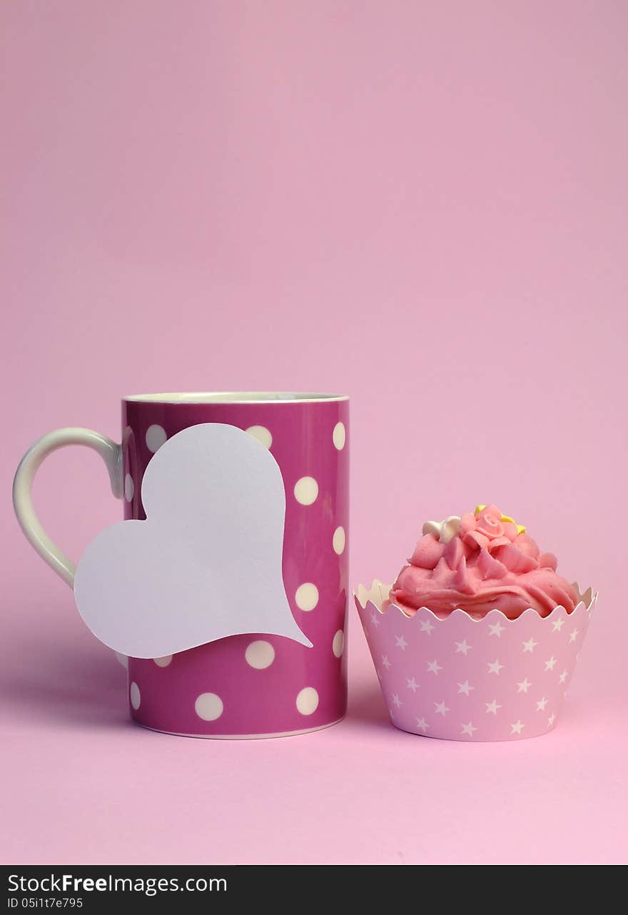 Pink polka dot coffee mug with pink cupcake and blank white heart shape gift tag for your text here, for female birthday, mothers day, or special occasion event. Vertical with copy space. Pink polka dot coffee mug with pink cupcake and blank white heart shape gift tag for your text here, for female birthday, mothers day, or special occasion event. Vertical with copy space.