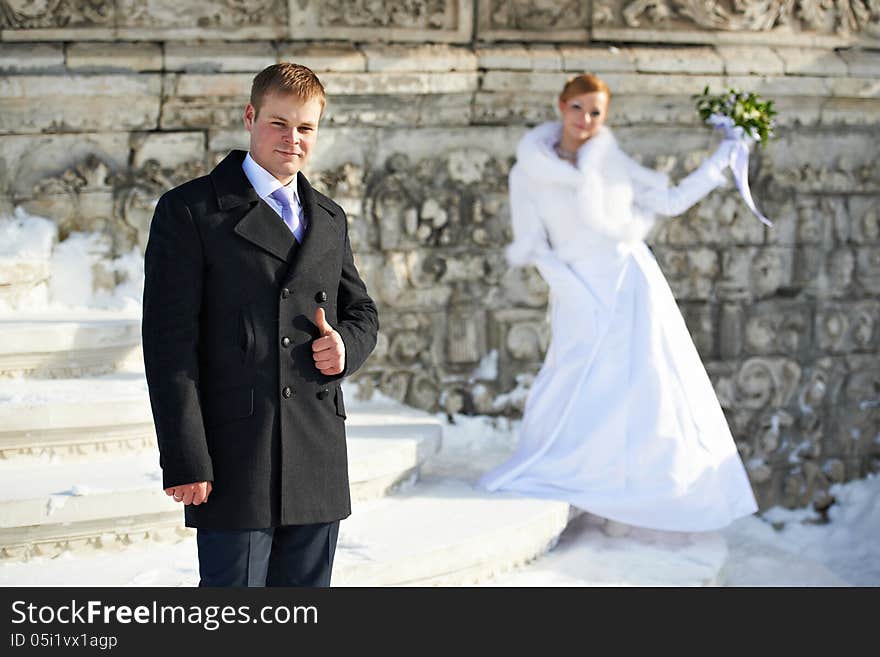 Happy bride and groom on wedding walk near stone wall background