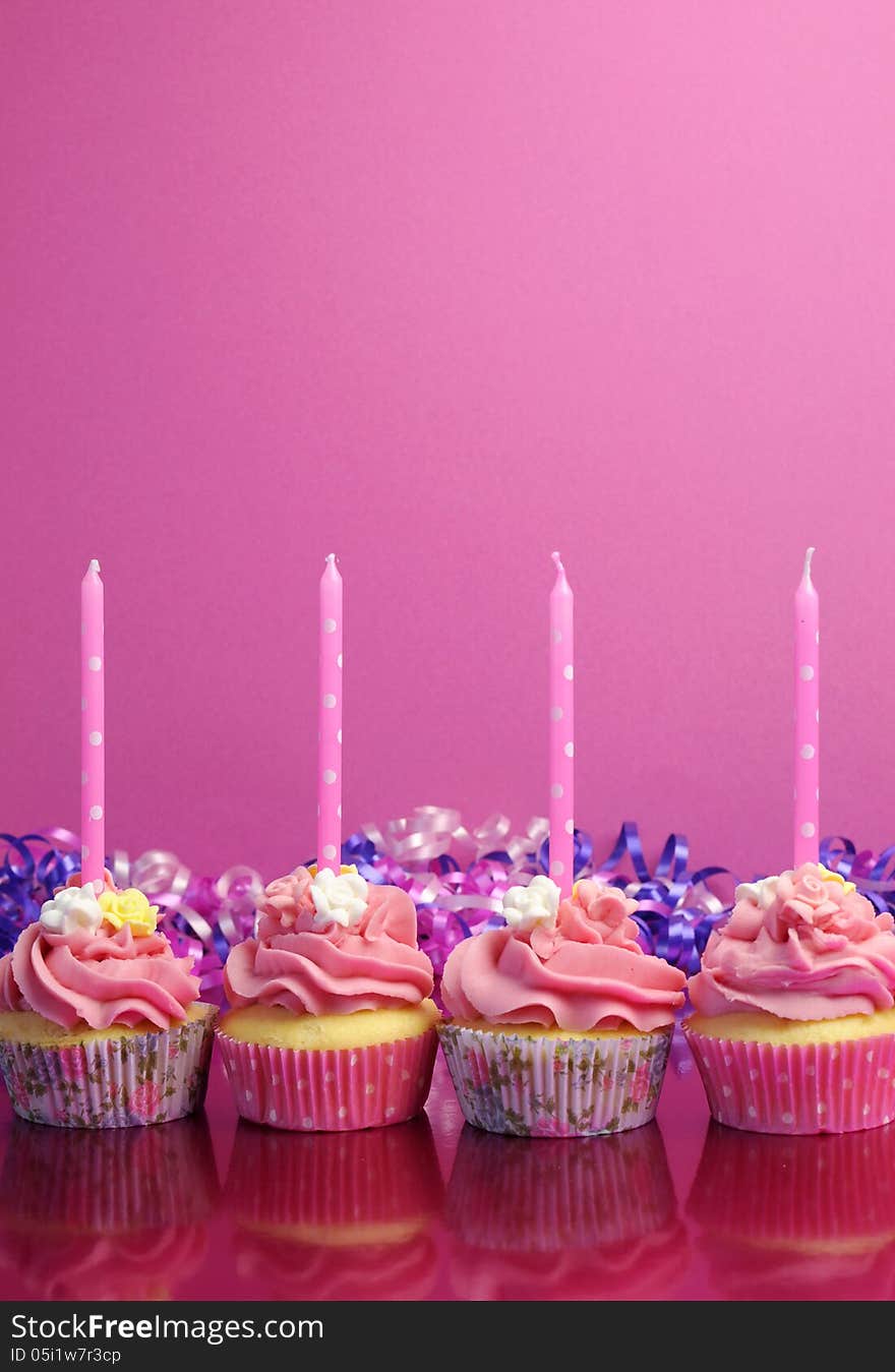 Pink birthday cupcakes with polka dot candles against a pink background. Vertical with copy space. Pink birthday cupcakes with polka dot candles against a pink background. Vertical with copy space.