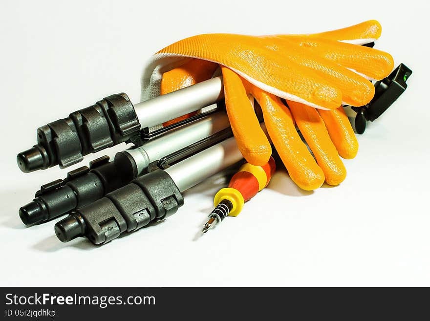 Gloves and tripod with screwdriver on white background.