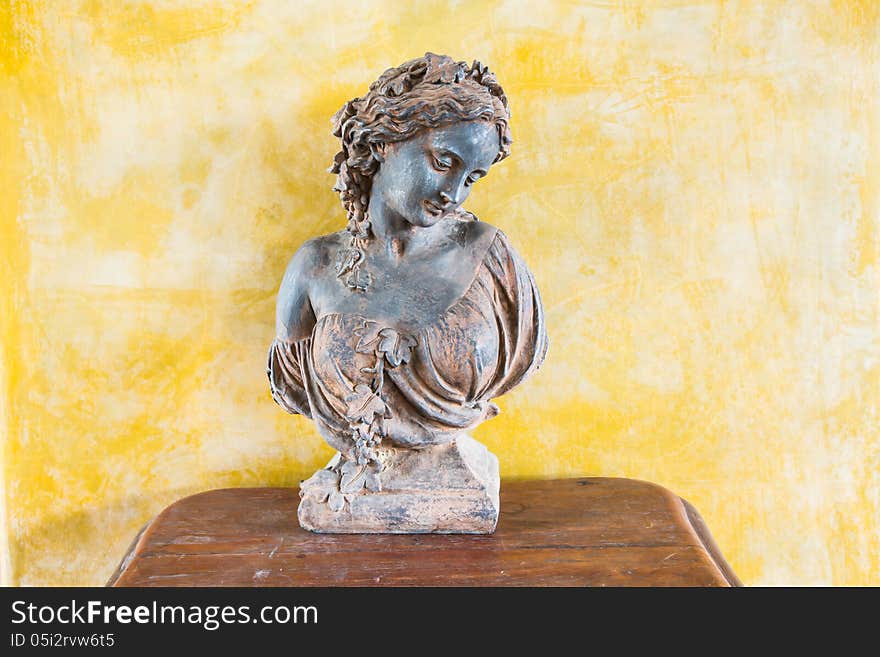 Bust of a beautiful lady on the table in front of yellow wall. Bust of a beautiful lady on the table in front of yellow wall.