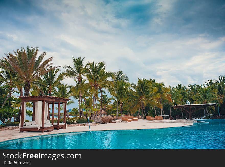 Outdoor resort pool. Swimming pool of luxury hotel. Swimming pool in luxury resort near the sea. Tropical Paradise. Swimming pool in spa resort. Dominican Republic, Seychelles, Caribbean, Bahamas. Outdoor resort pool. Swimming pool of luxury hotel. Swimming pool in luxury resort near the sea. Tropical Paradise. Swimming pool in spa resort. Dominican Republic, Seychelles, Caribbean, Bahamas.