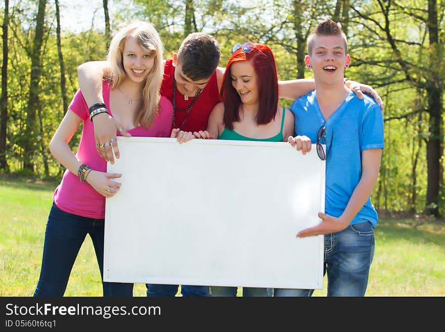 Four teenagers in colored shirts and a white board which can be used for your advertisements. Four teenagers in colored shirts and a white board which can be used for your advertisements