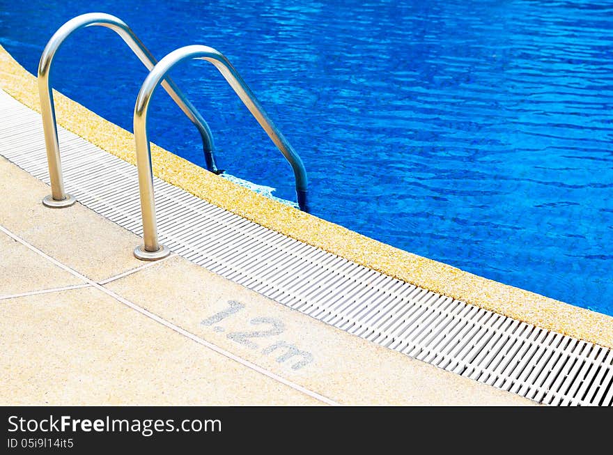 Grab bars ladder in the blue swimming pool