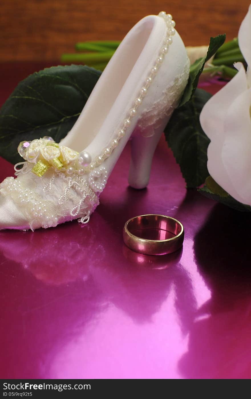 Wedding bridal bouquet of white roses on pink background with good luck shoe and wedding ring. Vertical with copy space.