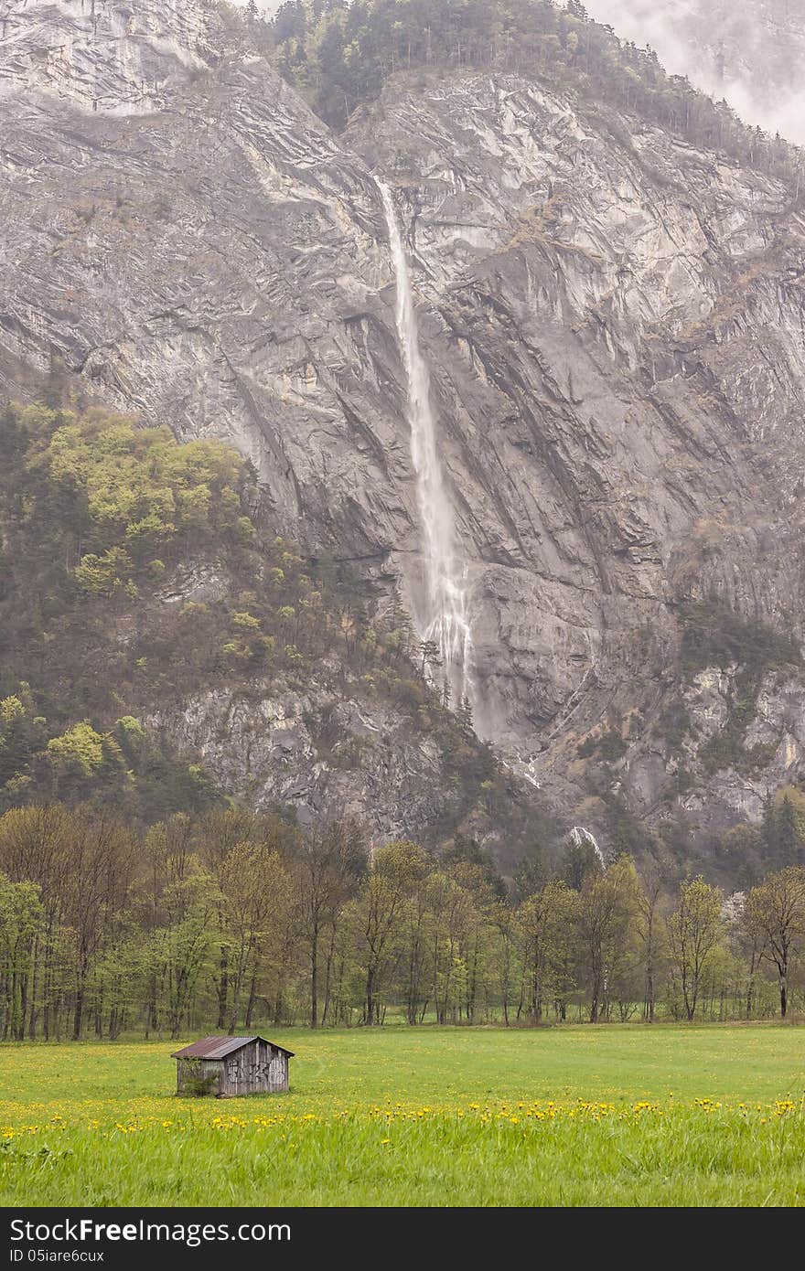 Beauty landscape. Wooden cottage in background big mountain and waterfall - France. Beauty landscape. Wooden cottage in background big mountain and waterfall - France.