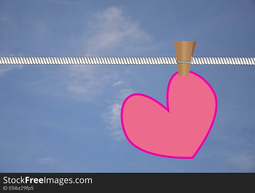 Pink heart hanged on white rope in front of blue sky