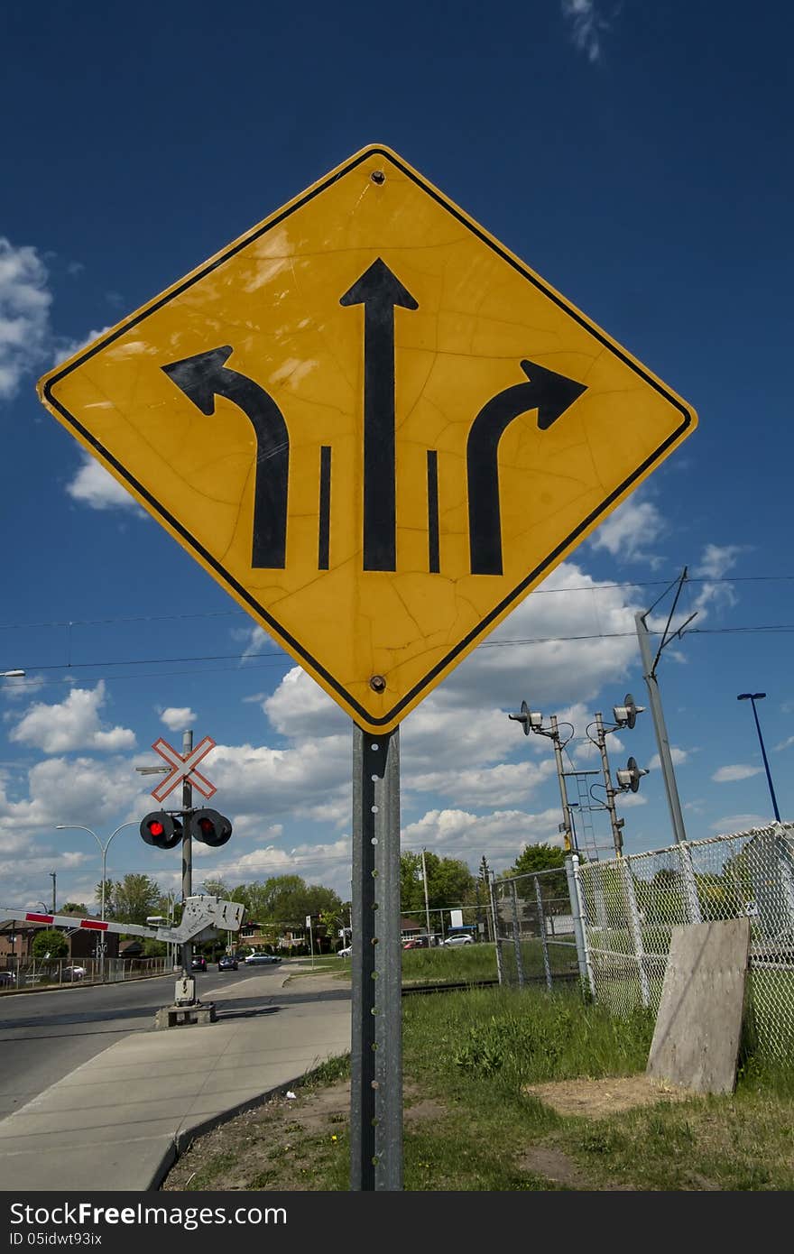 Direction road sign before a railroad crossing