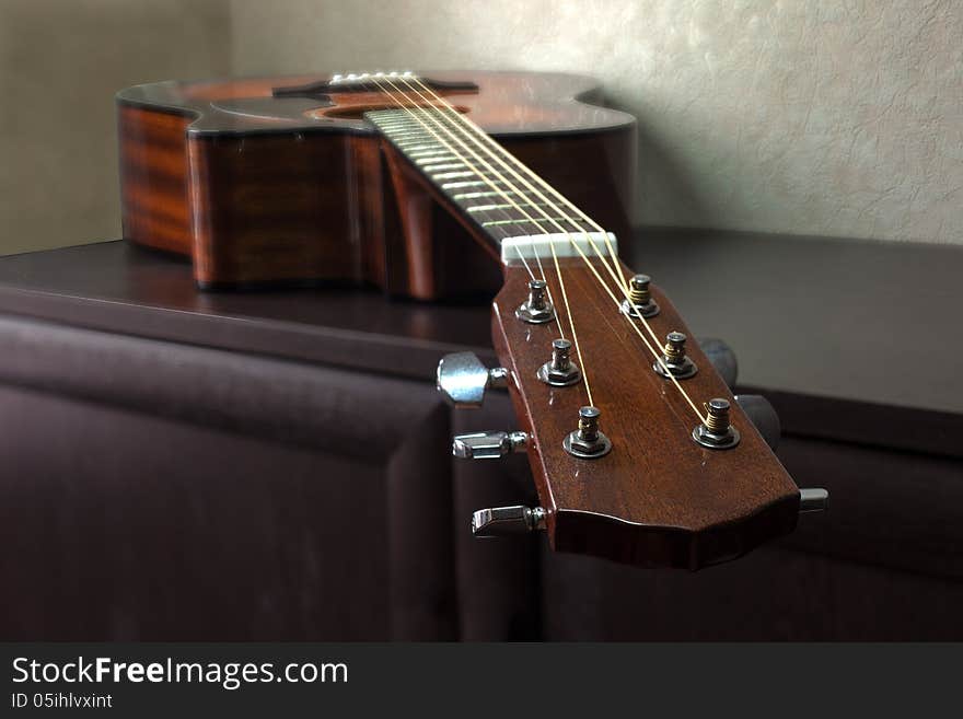 Brown six-string acoustic guitar lying on the table