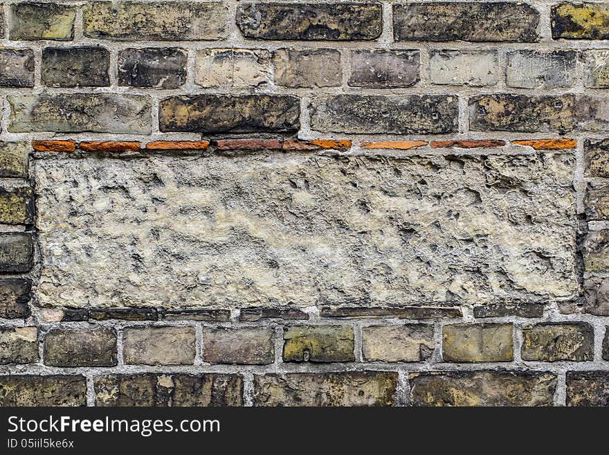 Old brick wall pattern closeup with rectangle of cement in the m