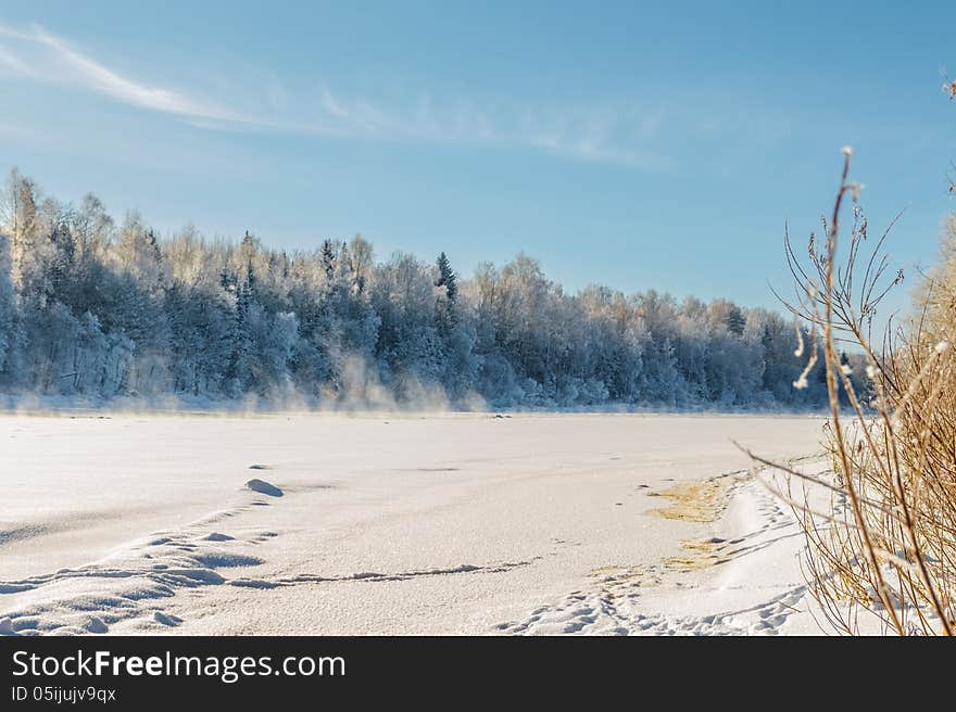 Dvina rver under ice. Not frozen sites of the river are in the distance noticeable. Over these sites steam rises. Landscape near Zdrawneva. The municipality of Ruba. Belarus. 2013. Dvina rver under ice. Not frozen sites of the river are in the distance noticeable. Over these sites steam rises. Landscape near Zdrawneva. The municipality of Ruba. Belarus. 2013.