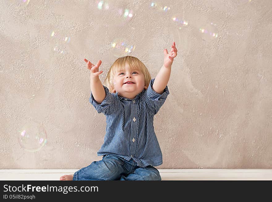 Cute little boy stretching up his arms to catch soap bubbles. Cute little boy stretching up his arms to catch soap bubbles