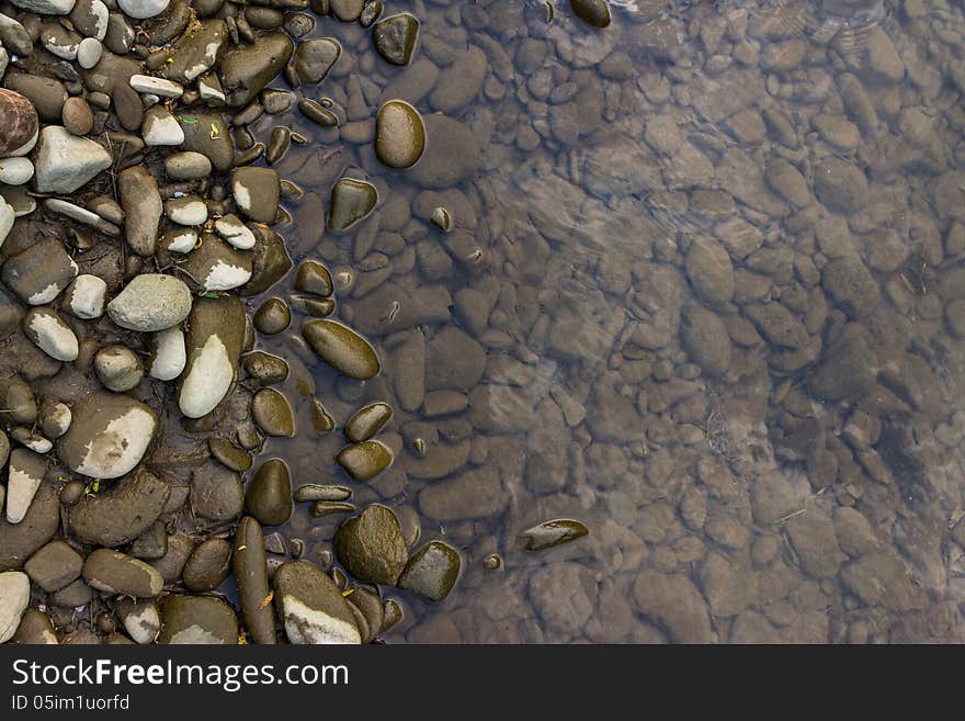 Narrow shore with smooth river stones, and gray water. Narrow shore with smooth river stones, and gray water