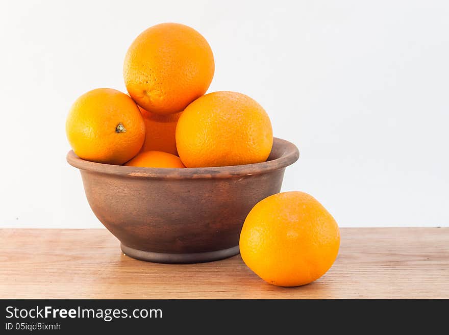 Still life of oranges in a clay bowl