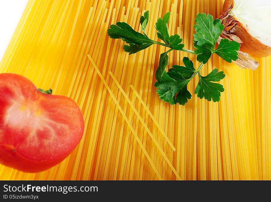 Raw spaghetti decorated with onion, tomato and parsley on white background