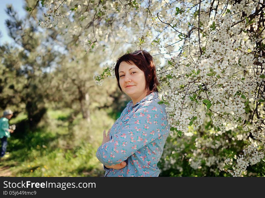 Girl in glasses on a background of a blossoming tree in spring in the garden