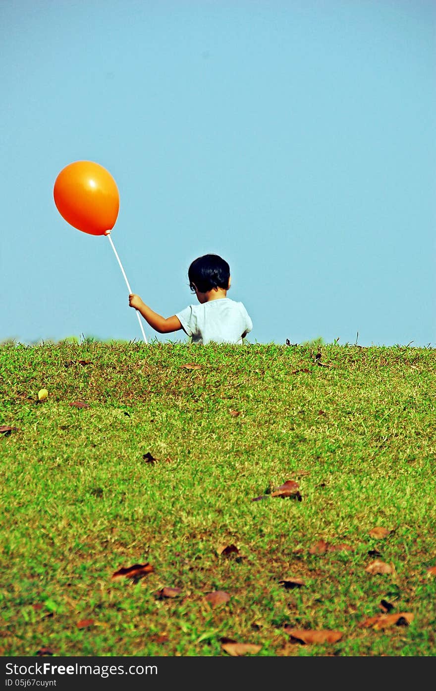 A kid running with flying balloon on green field. A kid running with flying balloon on green field.