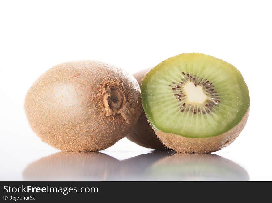 Kiwi fruit on a white background, reflected in the table. whole and sliced ​​fruit.