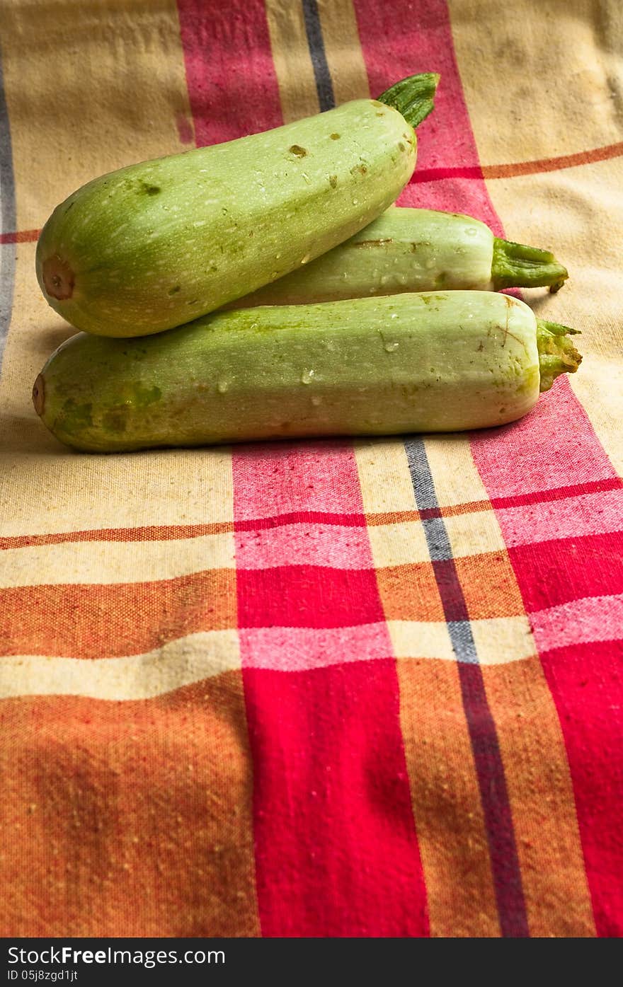 Wet zucchini on a colored tablecloths.