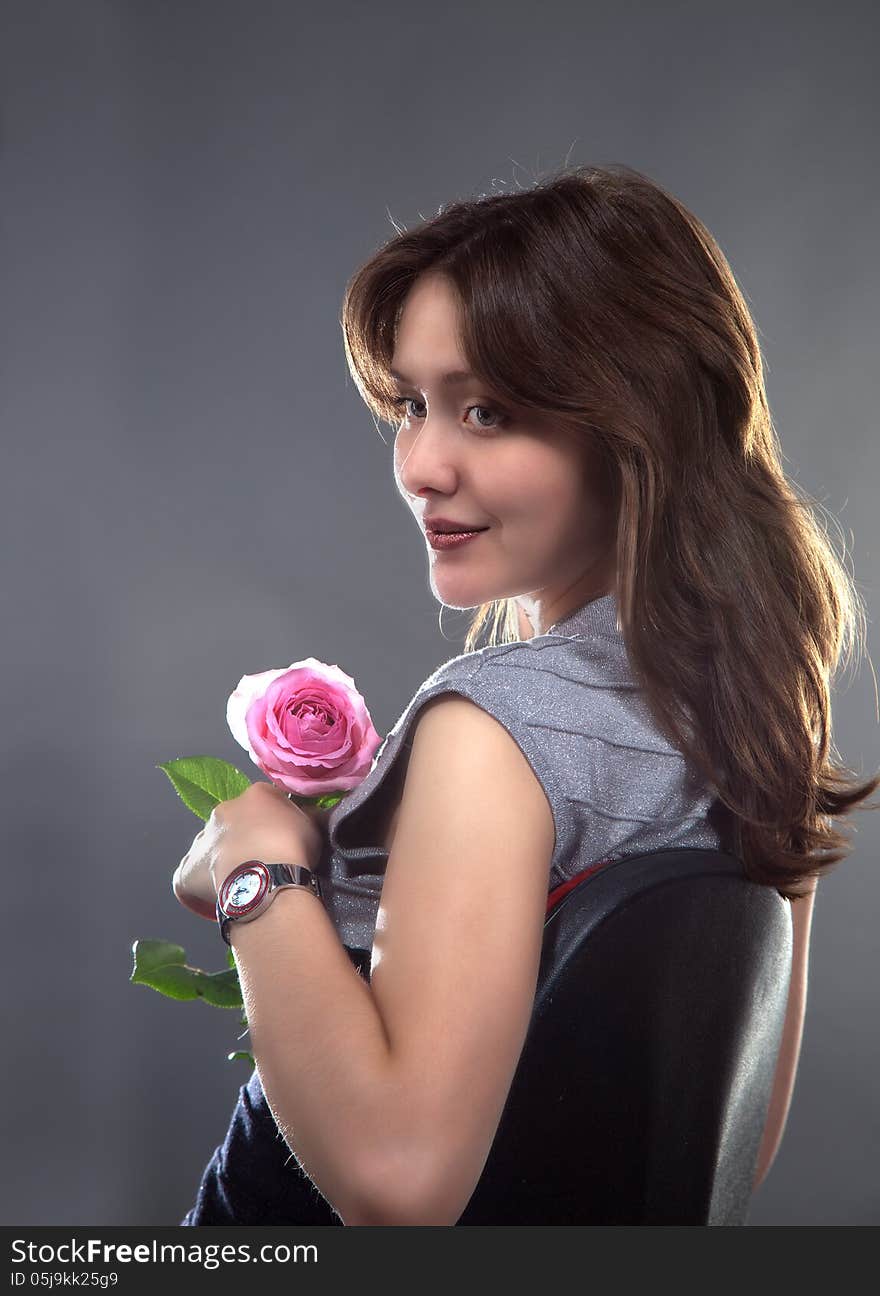 Portrait of a beautiful young girl with a pink rose