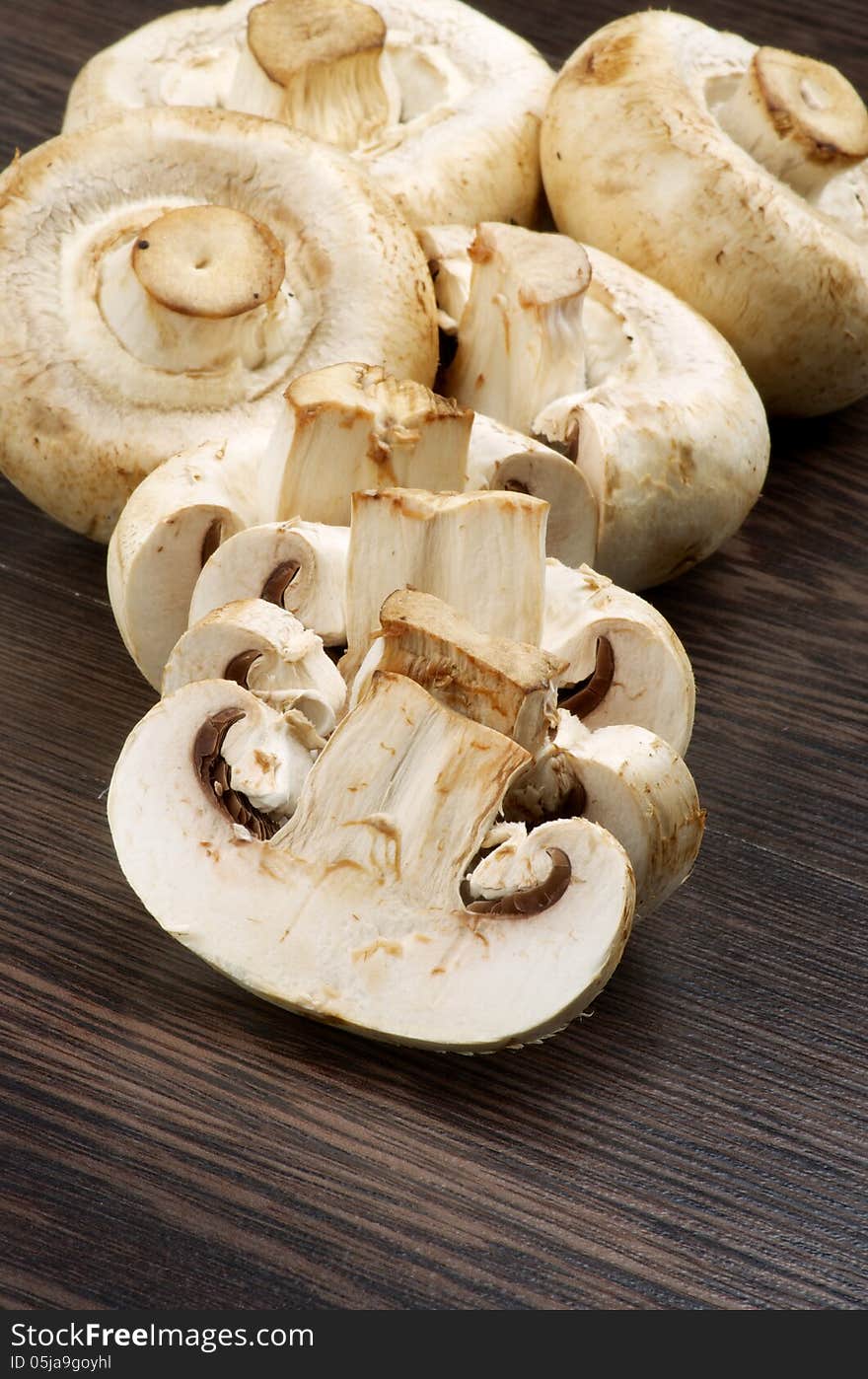 Heap of Big White Champignons Full Body and Slices on Dark Wood background. Heap of Big White Champignons Full Body and Slices on Dark Wood background