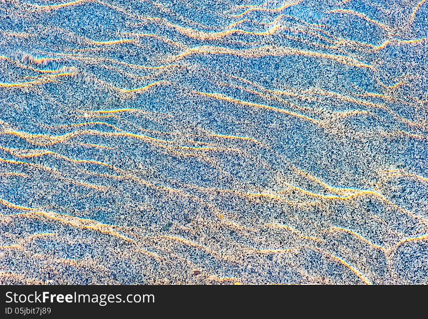 Sun reflections on a marble slab in pool water from above.