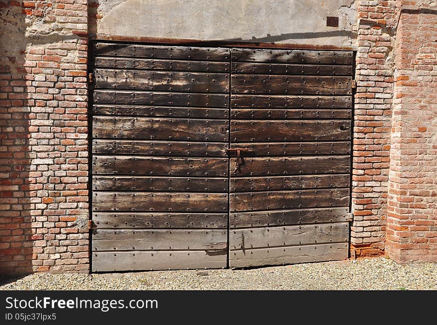 Ancient wood castle door and brick wall. Italian castele architecture. Ancient wood castle door and brick wall. Italian castele architecture