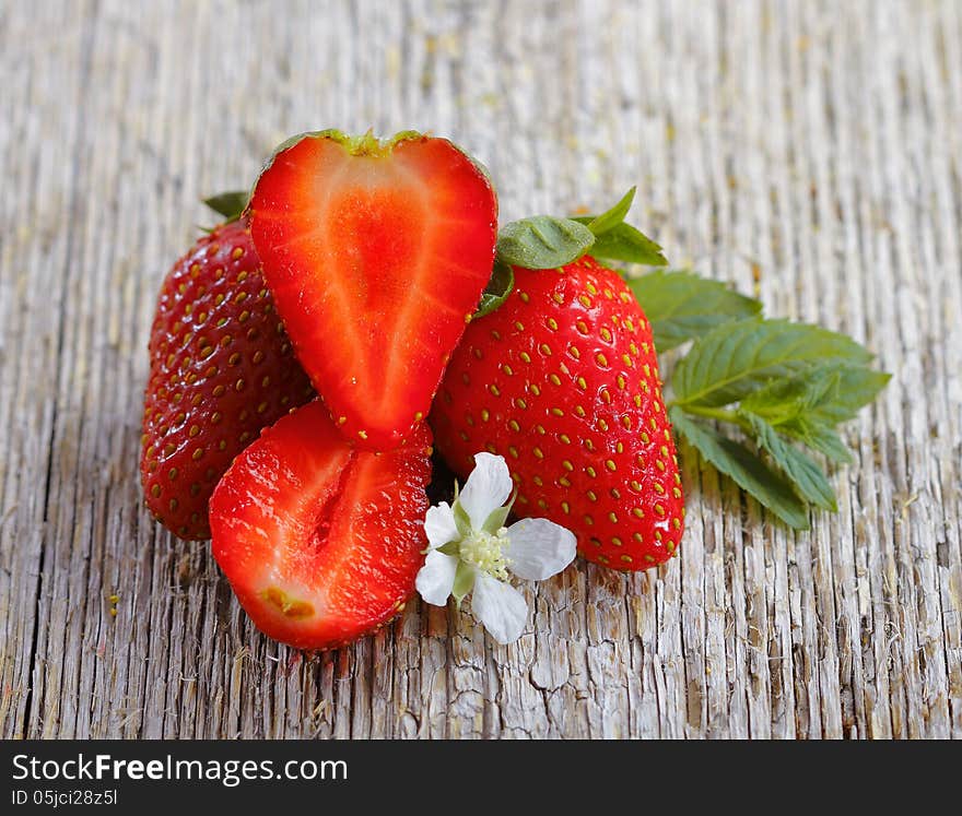 Fresh strawberries and two halves on a wood background. Fresh strawberries and two halves on a wood background