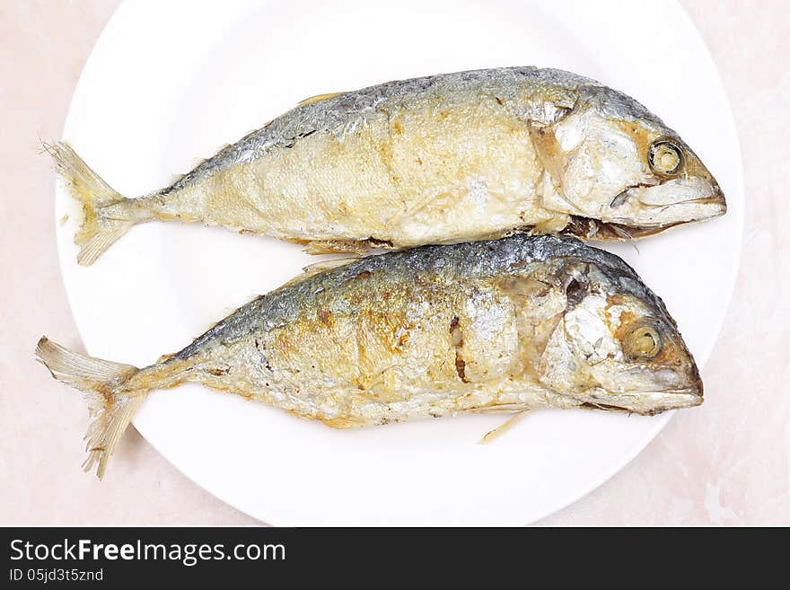 Two fried mackerel fishes on white plate