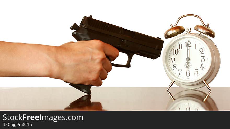 A hand with gun ready to fire at an alarm clock. A hand with gun ready to fire at an alarm clock