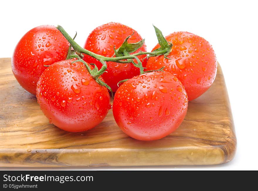 Fresh tomatoes on a branch on a wooden board isolated