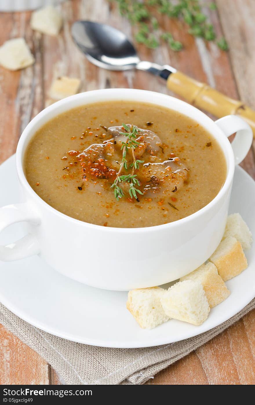 Mushroom cream soup with croutons and thyme in a bowl vertical