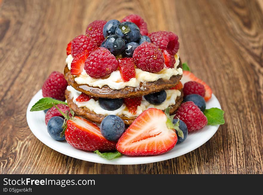 Pancake with whipped cream and fresh berries on the wooden table