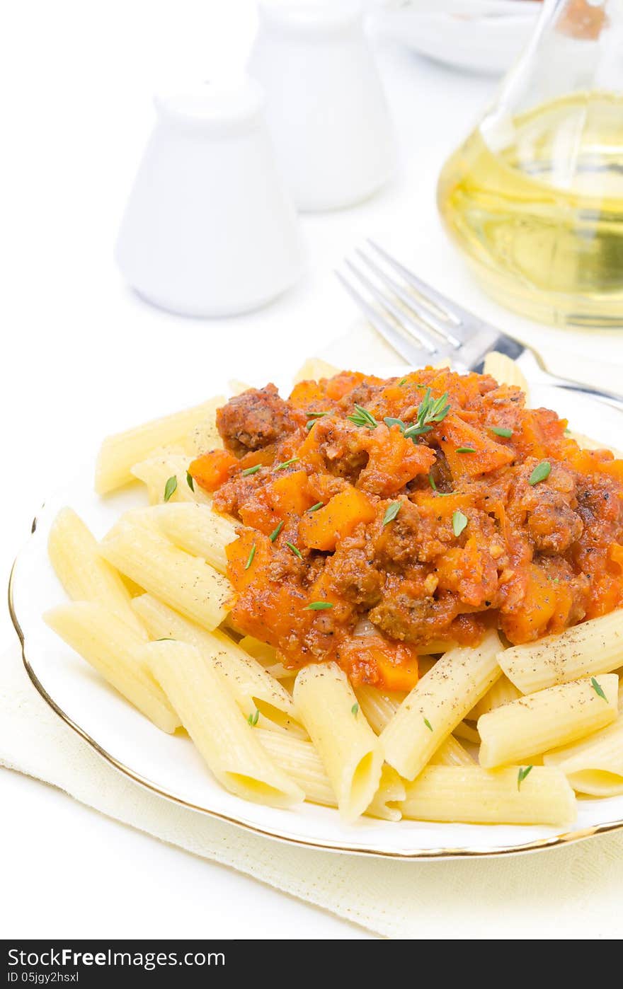 Penne pasta with sauce of beef, tomato and pumpkin on a plate isolated on white background, vertical