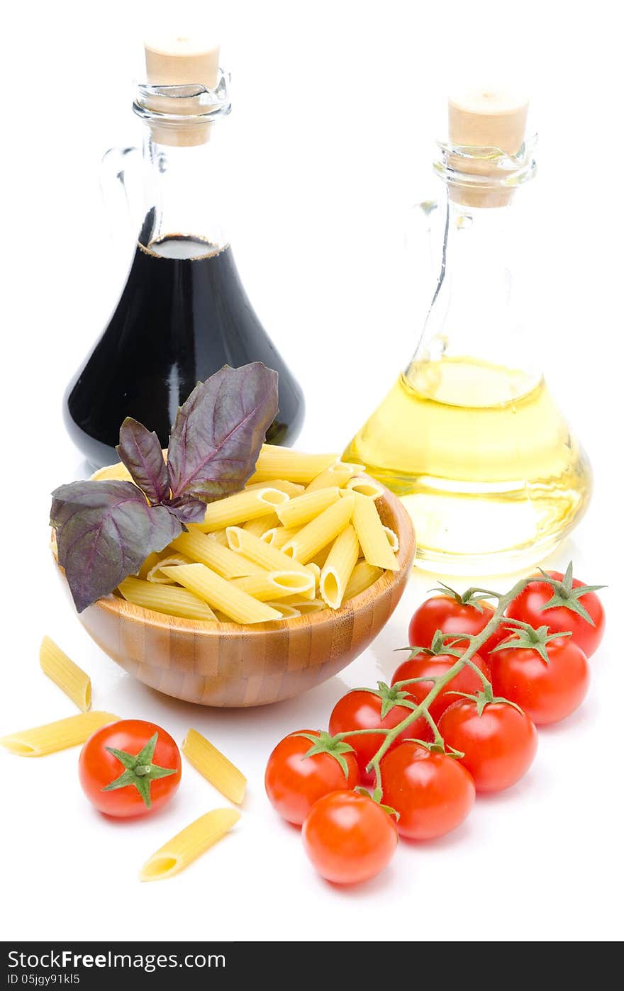 Penne pasta, fresh tomatoes, basil, olive oil and balsamic vinegar isolated on white background