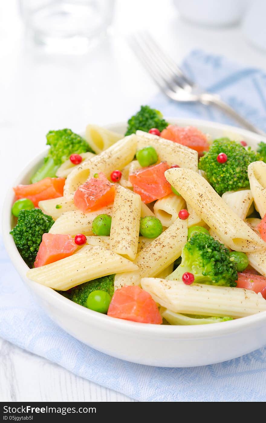 Salad with pasta, smoked salmon, broccoli and green peas closeup