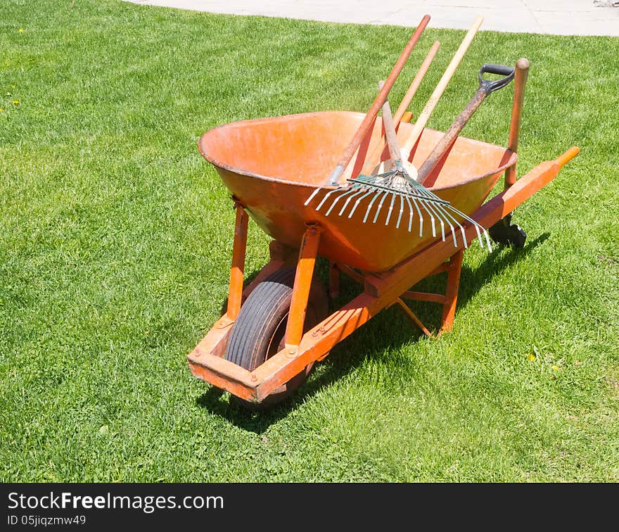 Orange wheelbarrow with garden tools