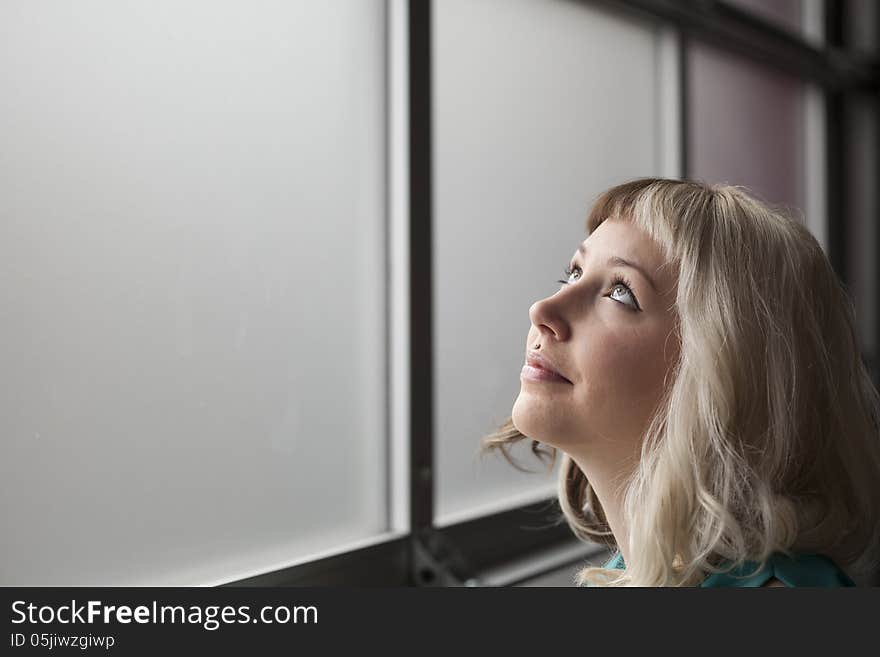 Portrait of a beautiful young woman with brown and blond hair looking up in the air.