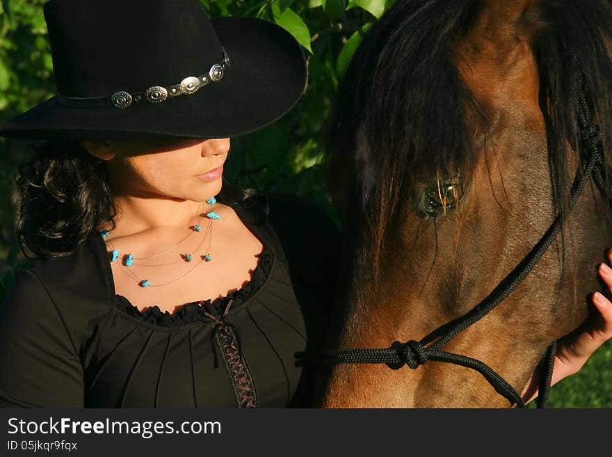 A cowgirl bonds with her horse at sunrise on the farm. A cowgirl bonds with her horse at sunrise on the farm