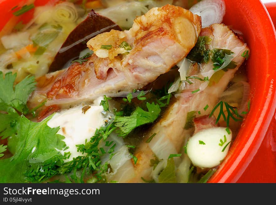 Vegetable Soup with Cabbage, Leek, Carrot, Garlic Greens, Smoked Pork Ribs and Sour Cream closeup in Red Bowl