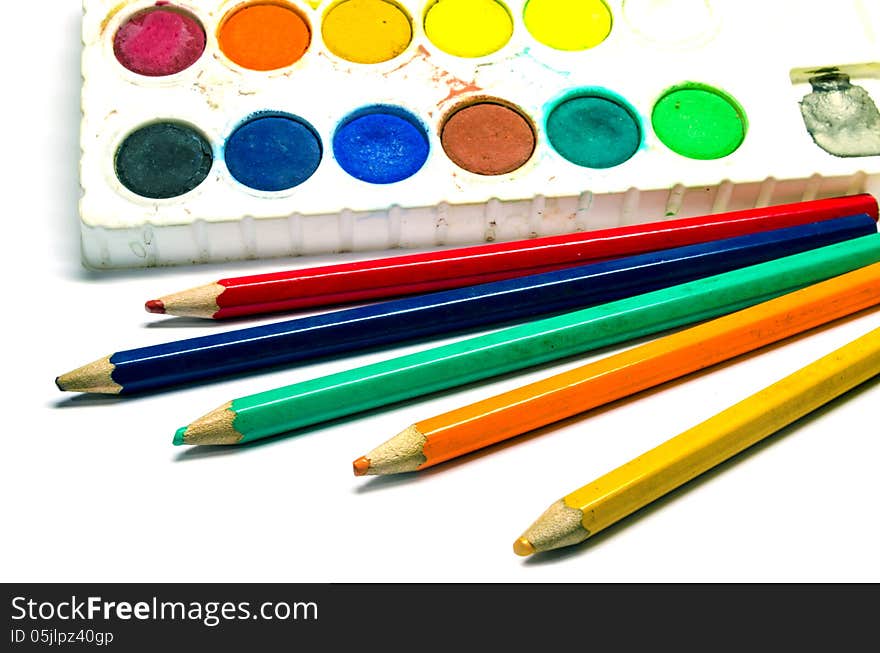 A dirty water color palette and color pencils isolated on white background